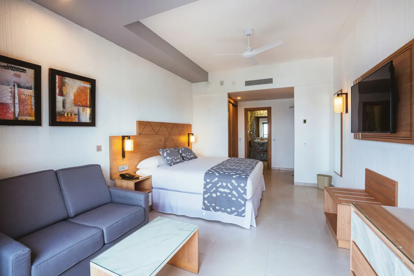 Garden view room with king bed, sofa, and TV at Hotel Riu Santa Fe.