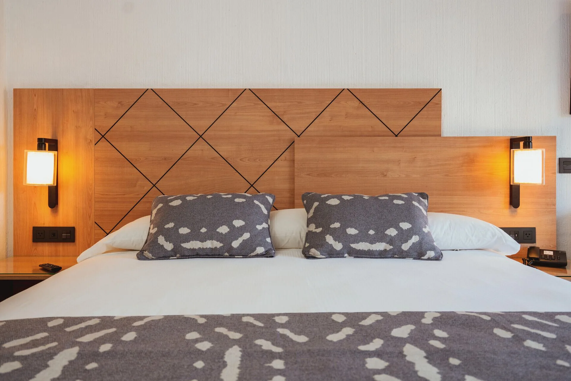 Room Partial Ocean View bed with wood headboard and wall lamps at Hotel Riu Santa Fe.
