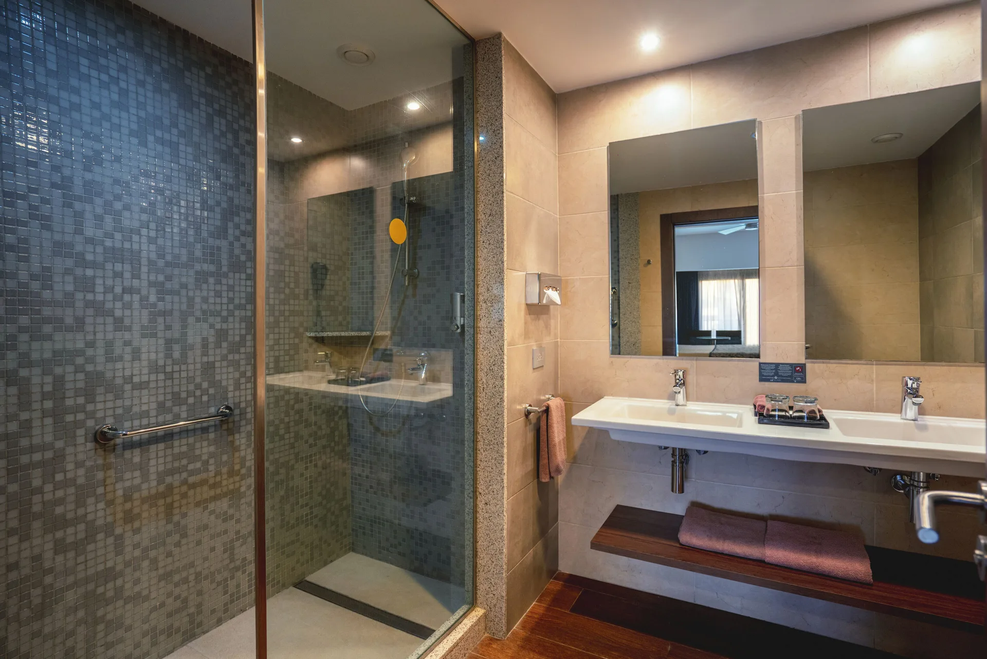 Guest room bathroom with glass shower, double sink, and large mirror at Hotel Riu Santa Fe.