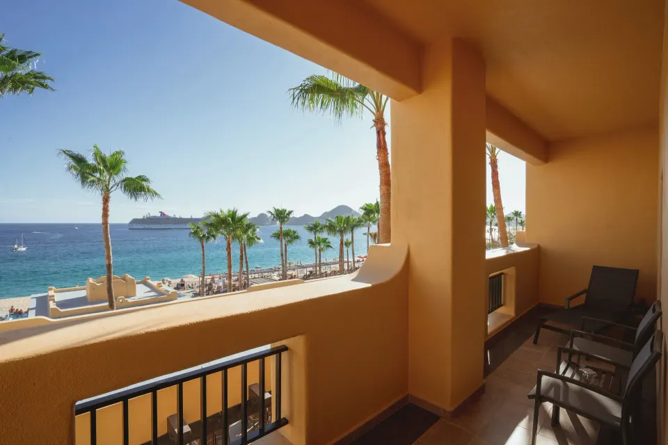 Suite Ocean View balcony overlooking palm trees and the sea at Hotel Riu Santa Fe.