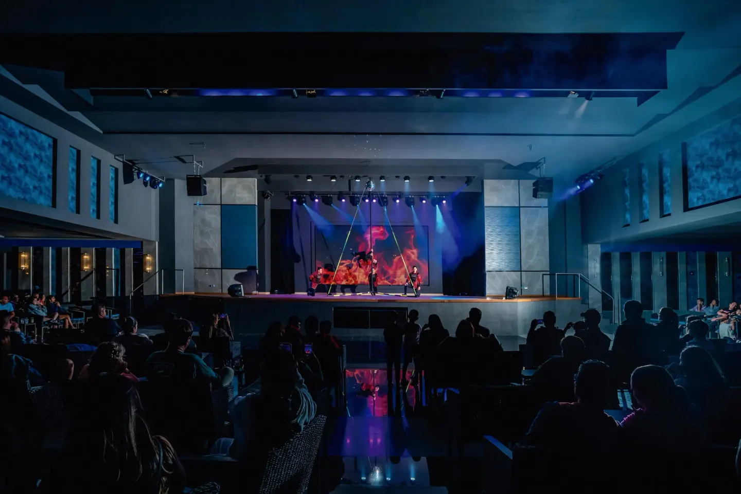 Audience watching a lit stage performance inside Hotel Riu Santa Fe.
