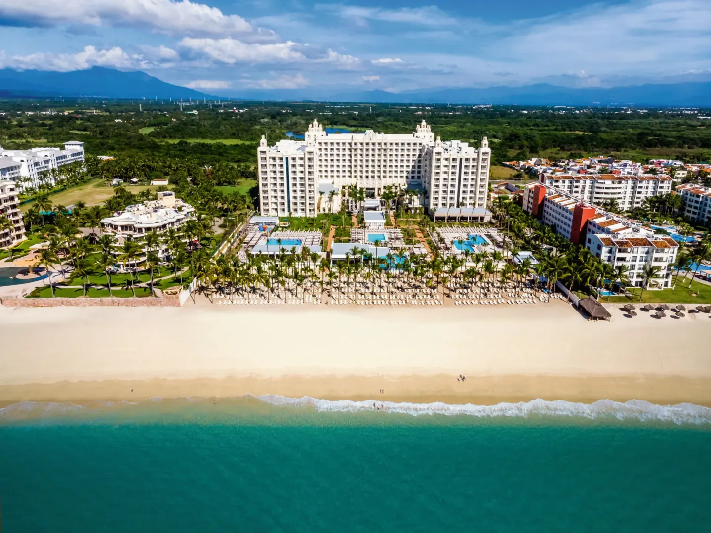 Aerial beachfront view of Hotel Riu Vallarta with pools, palms and ocean.