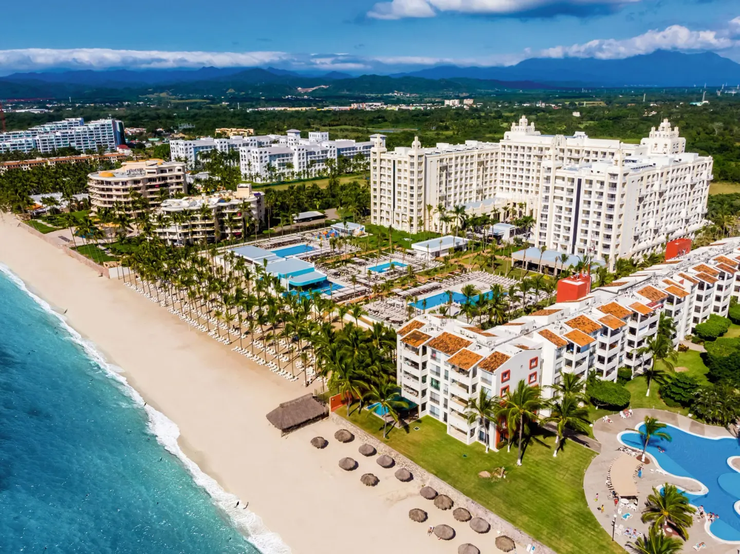 Angled aerial view of Hotel Riu Vallarta beside the beach and pools.