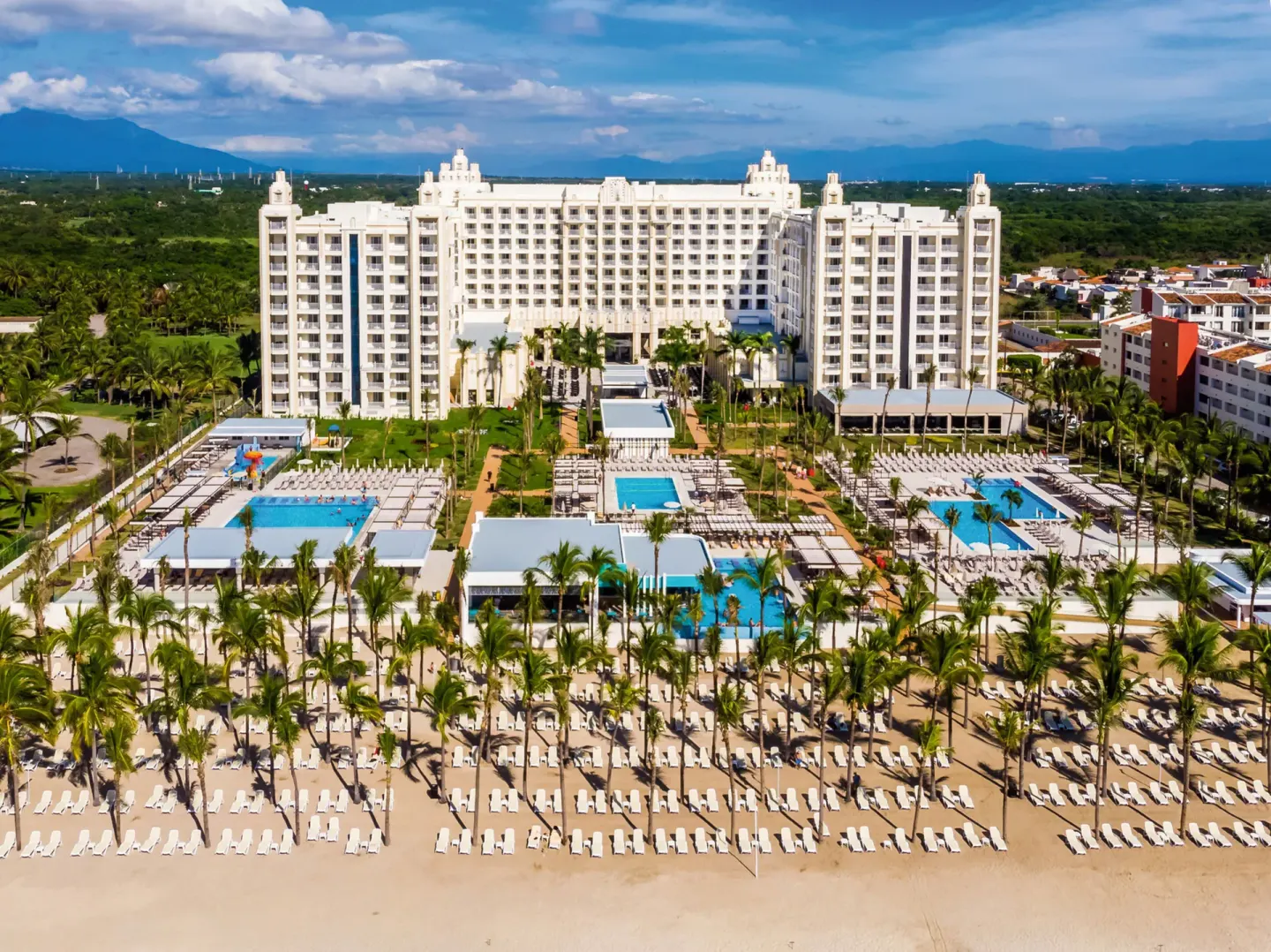 Beachfront pools, palms, and main building at Hotel Riu Vallarta.