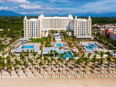 Beachfront pools, palms, and main building at Hotel Riu Vallarta.