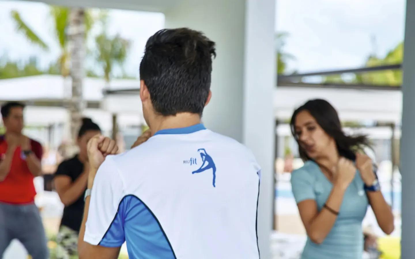 Instructor leads guests through a group fitness class in an open pavilion at Hotel Riu Vallarta.