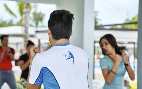 Instructor leads guests through a group fitness class in an open pavilion at Hotel Riu Vallarta.