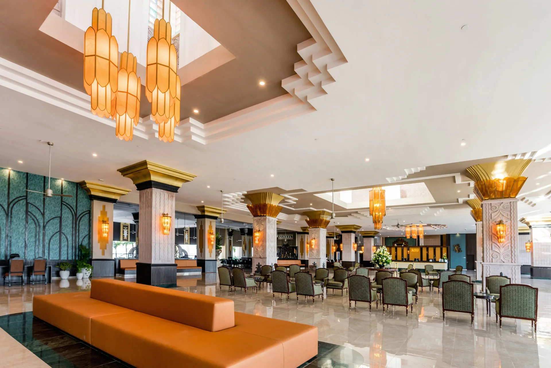 Lobby lounge with orange sofa, chairs, and decorative columns at Hotel Riu Vallarta.