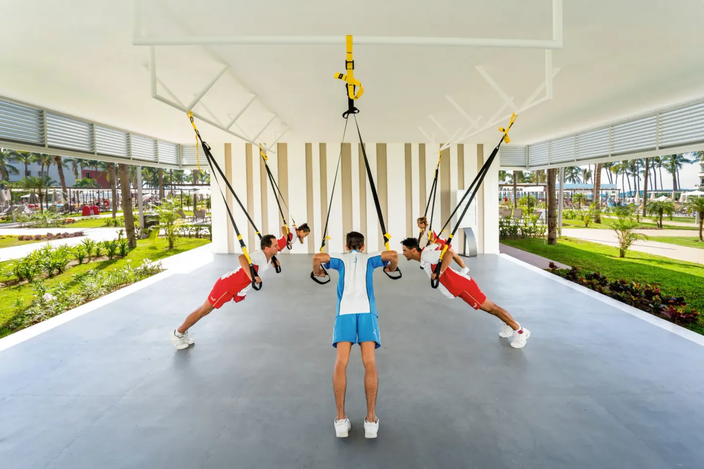 Guests use suspension straps in an open-air fitness class at Hotel Riu Vallarta.