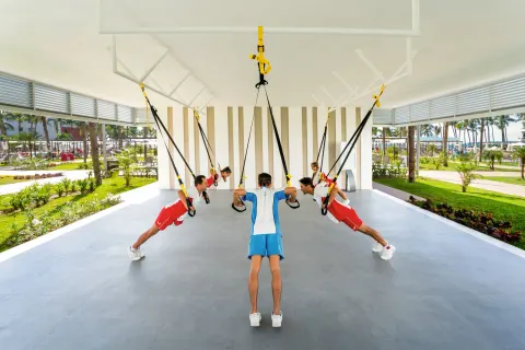 Guests use suspension straps in an open-air fitness class at Hotel Riu Vallarta.