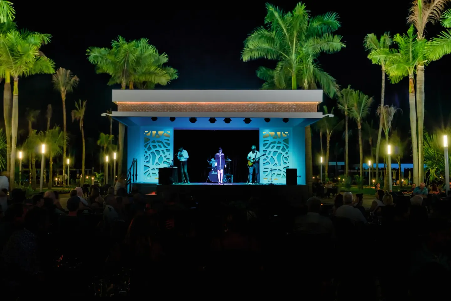 Musicians perform on an outdoor stage surrounded by palms at Hotel Riu Vallarta.
