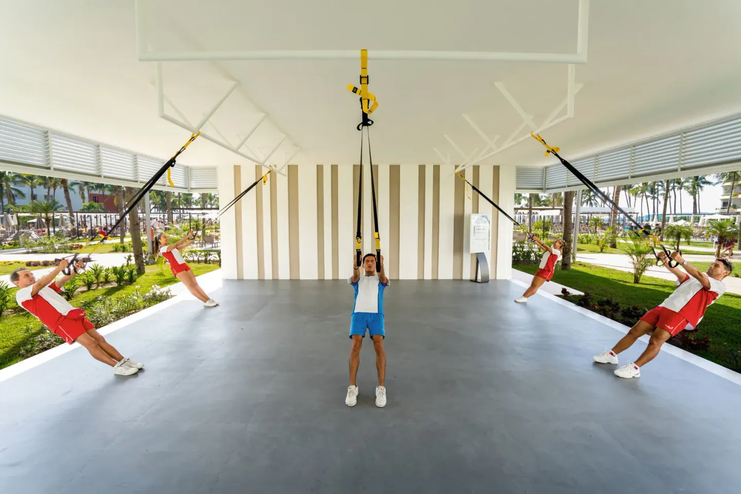 Guests lean back on suspension straps during an outdoor fitness class at Hotel Riu Vallarta.