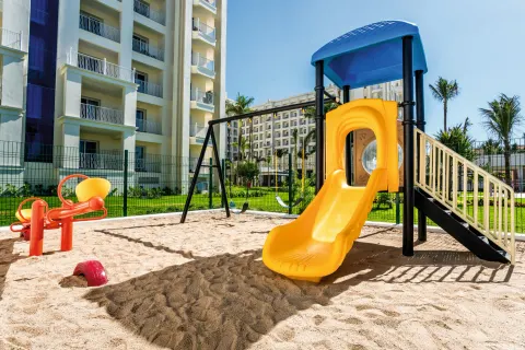 Playground slide and seesaw beside resort buildings at Hotel Riu Vallarta.