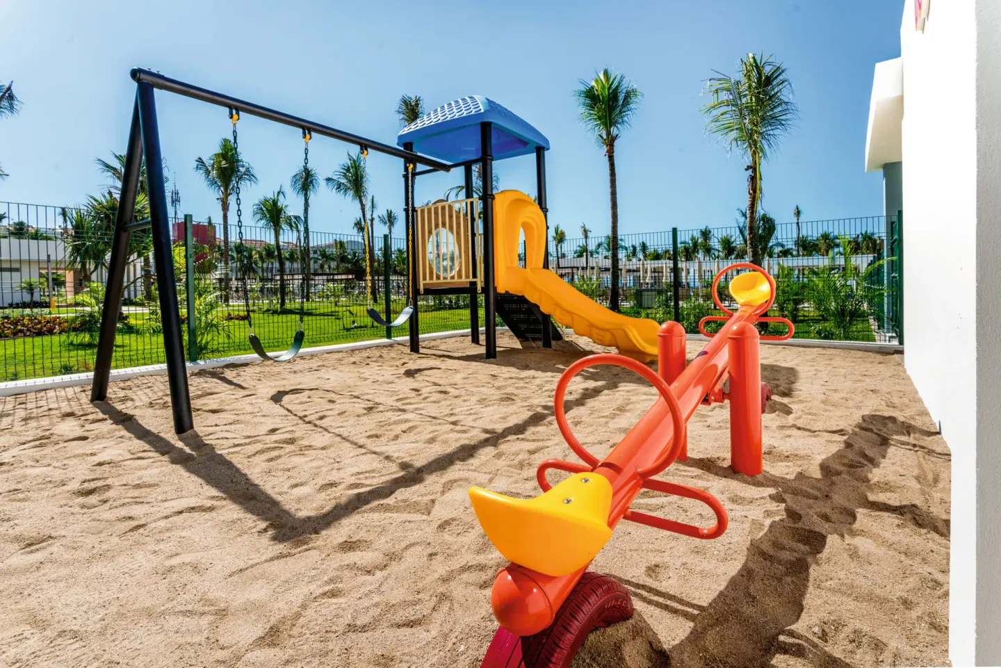 Sandy playground with swings, slide, and seesaw at Hotel Riu Vallarta.