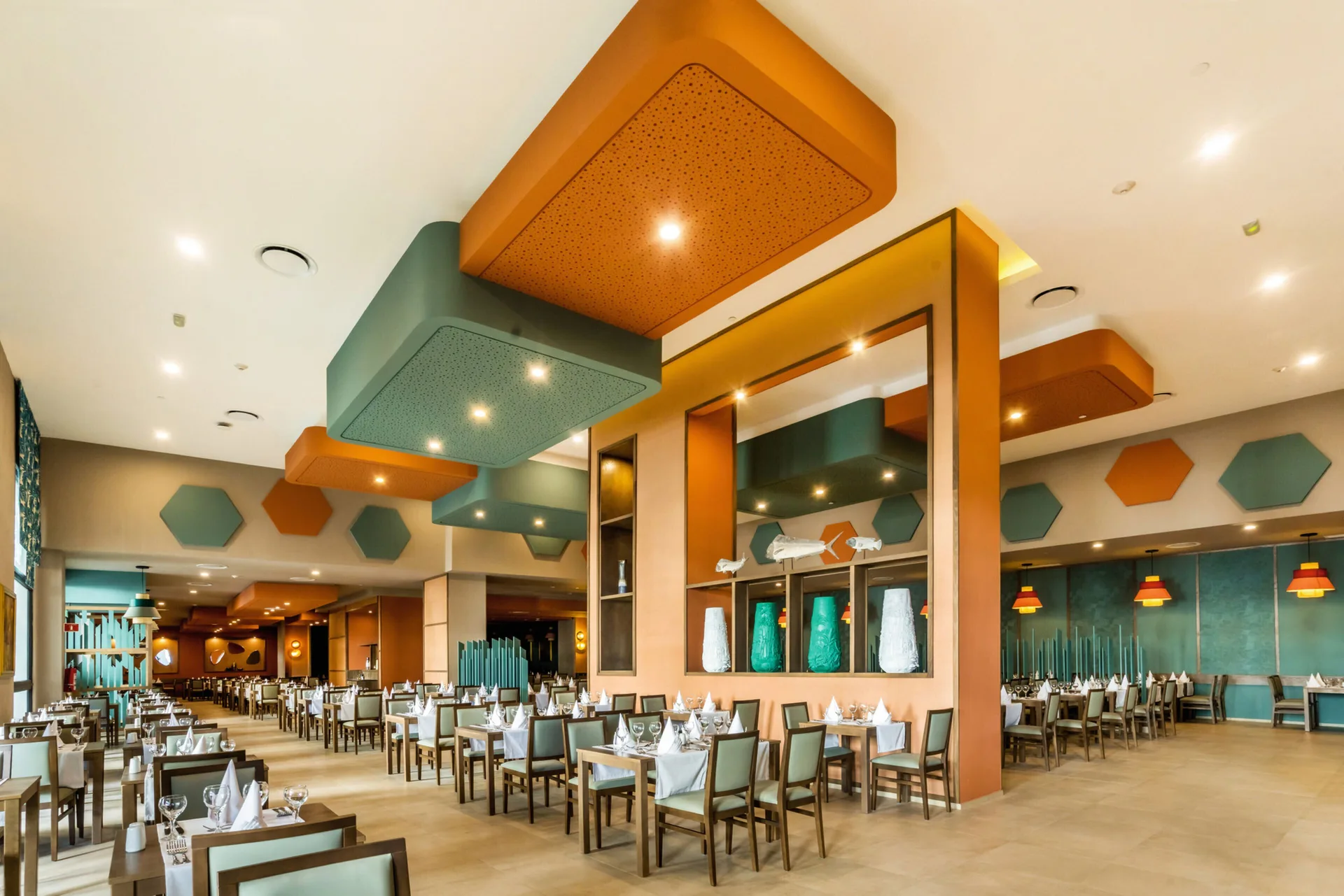 Spacious dining room with set tables and colorful ceiling panels at Hotel Riu Vallarta.