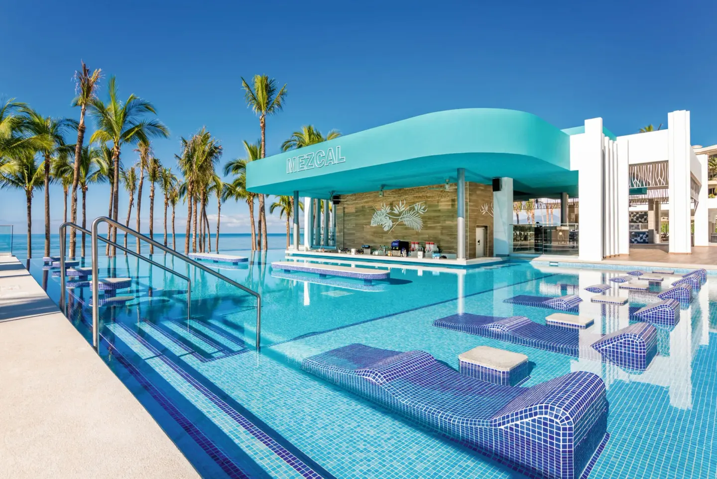 Mezcal swim-up pool bar with ocean and palm trees at Hotel Riu Vallarta.