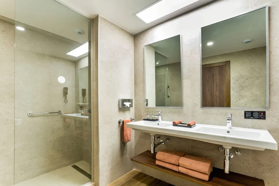 Family Room bathroom with double sink and glass shower at Hotel Riu Vallarta.