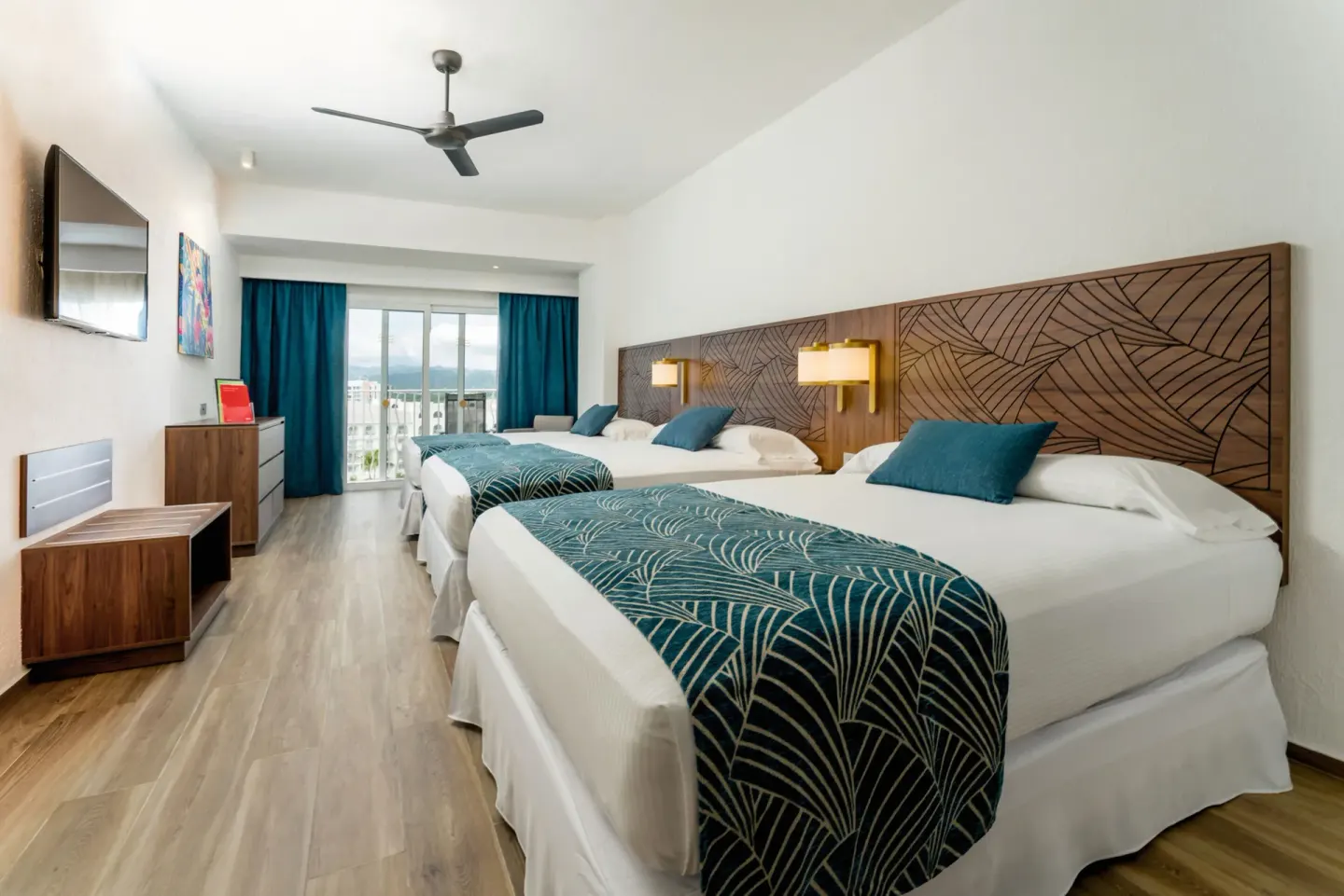 Family Room with three beds and balcony doors at Hotel Riu Vallarta.