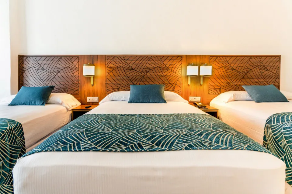 Family Room beds with teal leaf-patterned runners at Hotel Riu Vallarta.