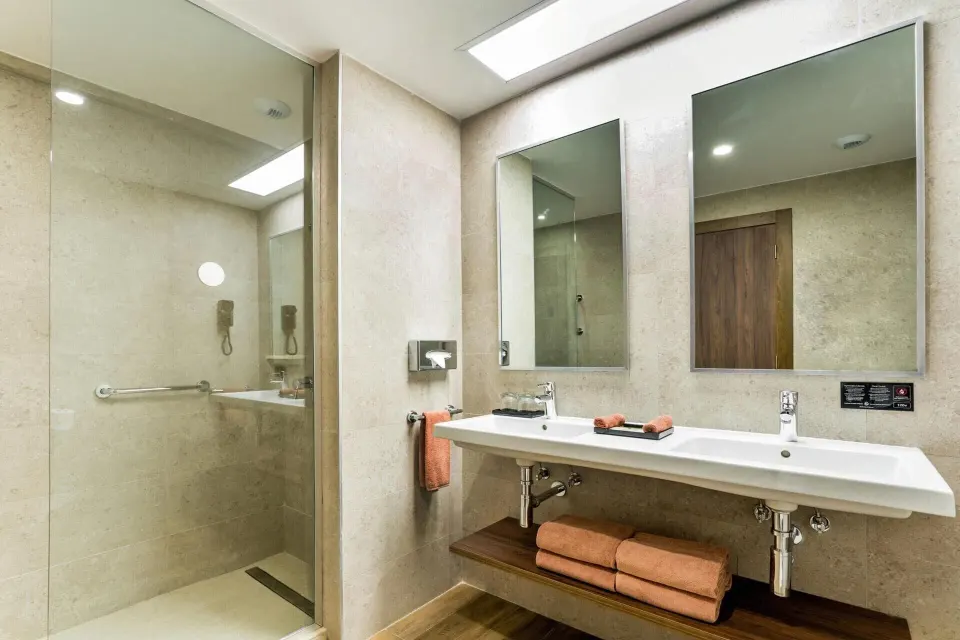 Family Room bathroom with double sink vanity and glass shower at Hotel Riu Vallarta.