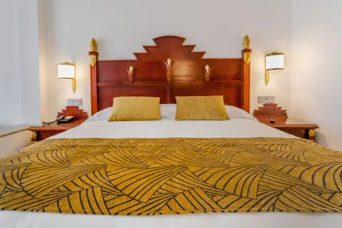 Ocean View Junior Suite king bed with carved headboard at Hotel Riu Vallarta.