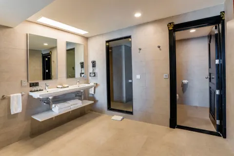 Ocean View Suite bathroom with double sink, mirrors, towels, and shower area at Hotel Riu Vallarta.