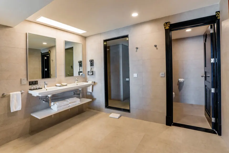 Ocean View Suite bathroom with double sink, mirrors, towels, and shower area at Hotel Riu Vallarta.