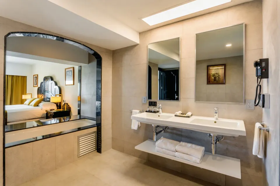 Ocean View Suite bathroom with twin mirrors, long vanity, and bedroom view at Hotel Riu Vallarta.