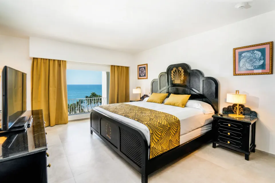Ocean View Suite bedroom with king bed and balcony sea view at Hotel Riu Vallarta.