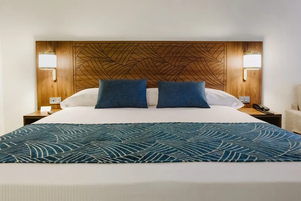 Close-up of a king bed with patterned headboard at Hotel Riu Vallarta.
