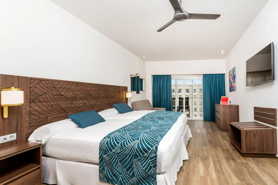 Standard Room with two beds and balcony doors at Hotel Riu Vallarta.