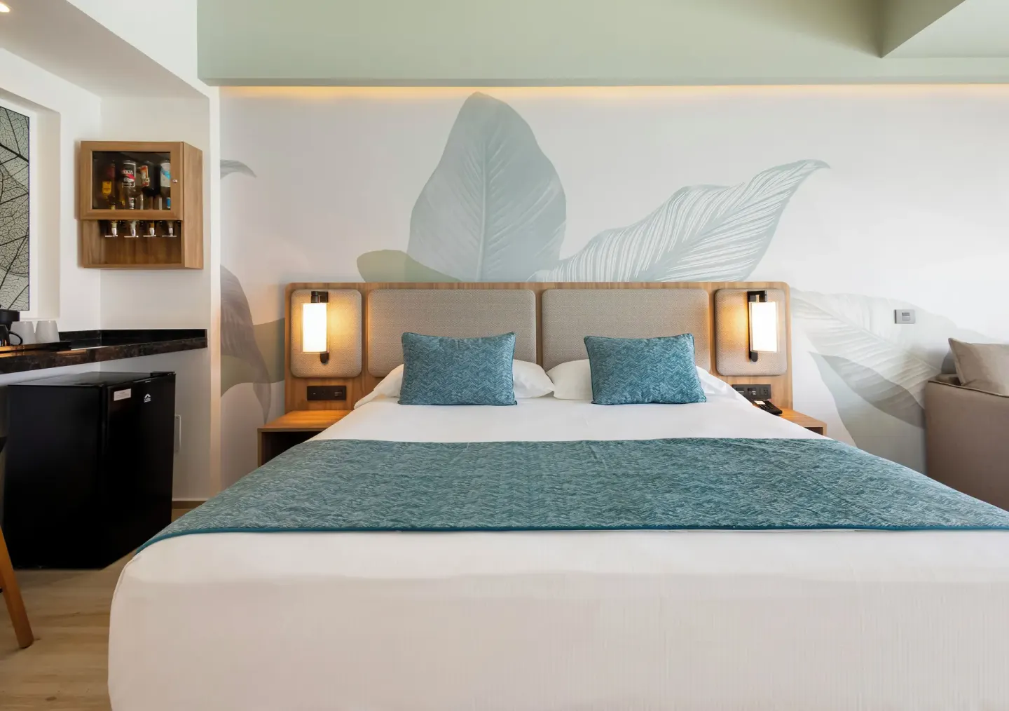 Oceanfront swim-up room king bed with leaf mural and refreshment nook at Hotel Riu Ventura.