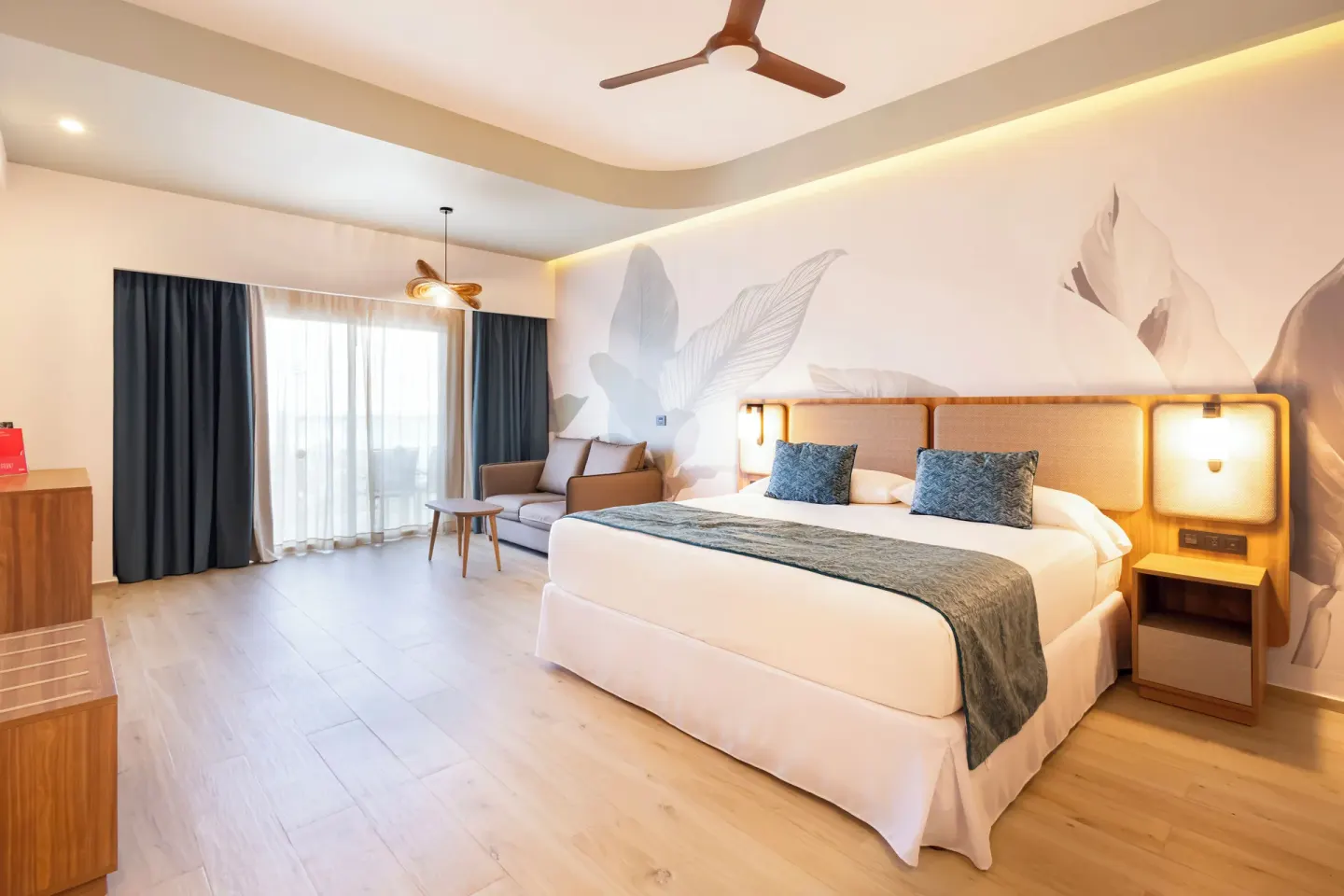 King bed and balcony doors in a partial ocean view room at Hotel Riu Ventura.