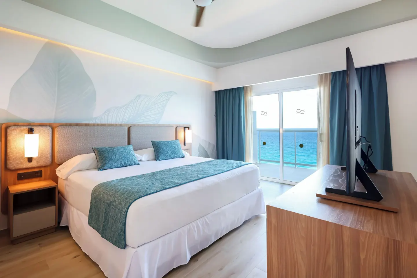 Oceanfront suite king bed with balcony doors and sea view at Hotel Riu Ventura.