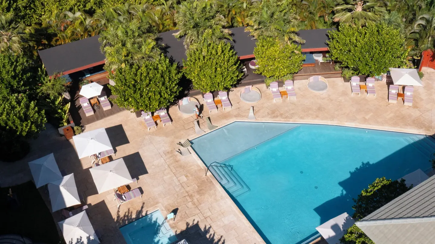 Aerial view of the resort pool deck with umbrellas, loungers, and trees at Hotel Wailea.