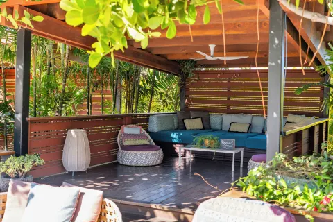 Covered pool cabana with sectional seating, pillows, and tropical plants at Hotel Wailea.