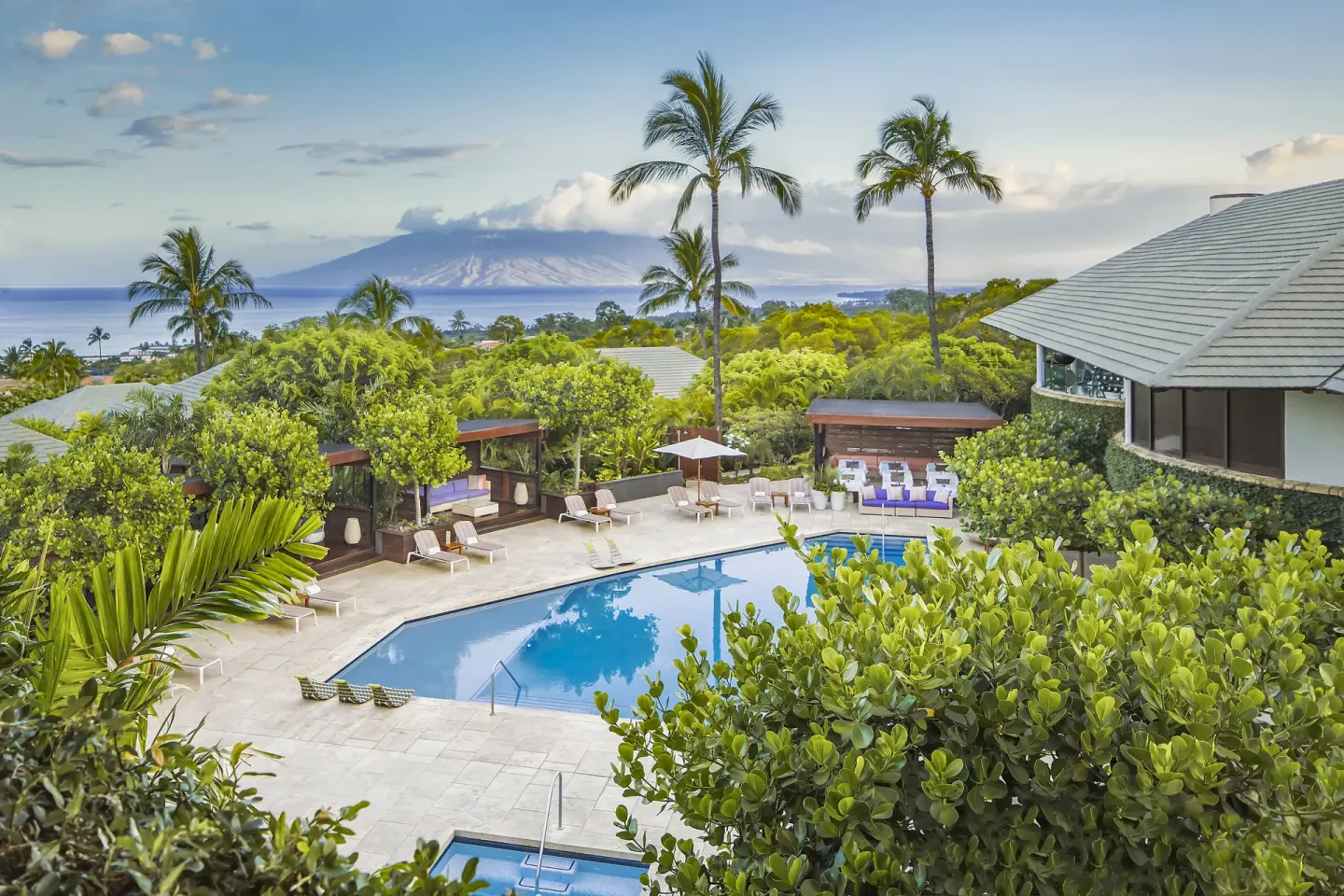 Elevated pool view with palms, cabanas, ocean, and distant island at Hotel Wailea.