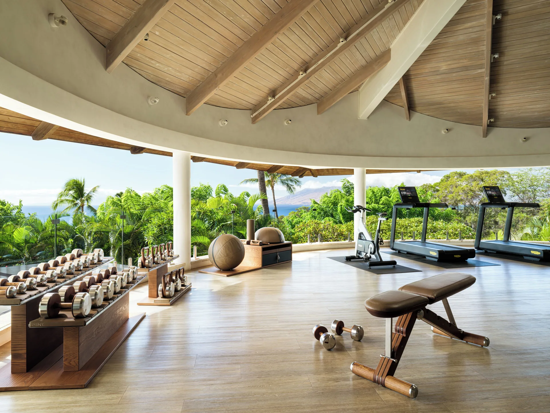 Open-air fitness room with weights, treadmills, bike, and greenery at Hotel Wailea.