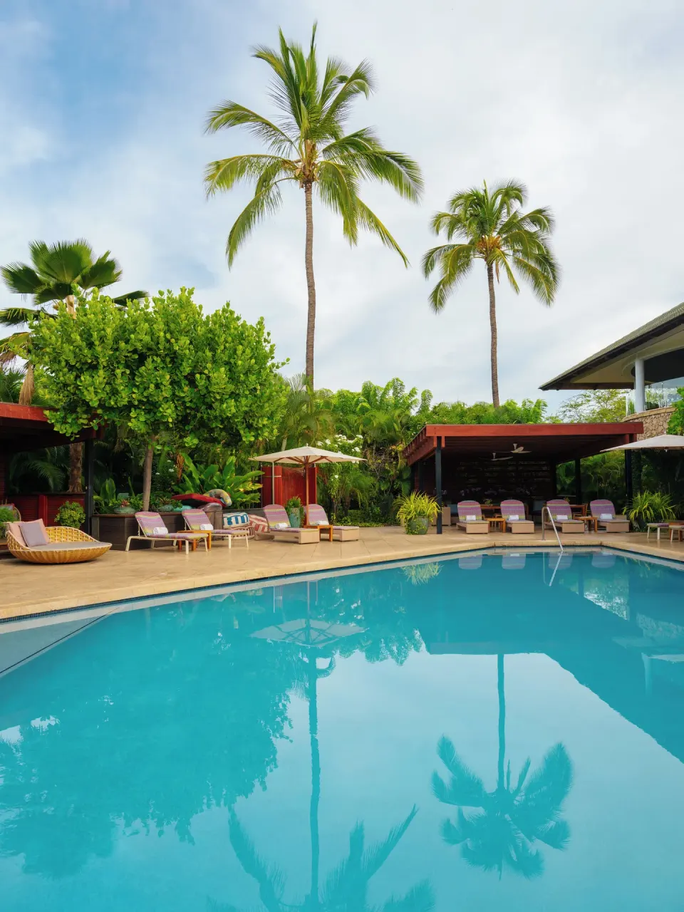 Resort pool with palm reflections, loungers, umbrellas, and cabanas at Hotel Wailea.