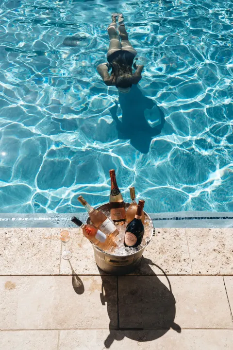 A swimmer glides through the pool near an ice bucket of sparkling wine at Hotel Wailea.