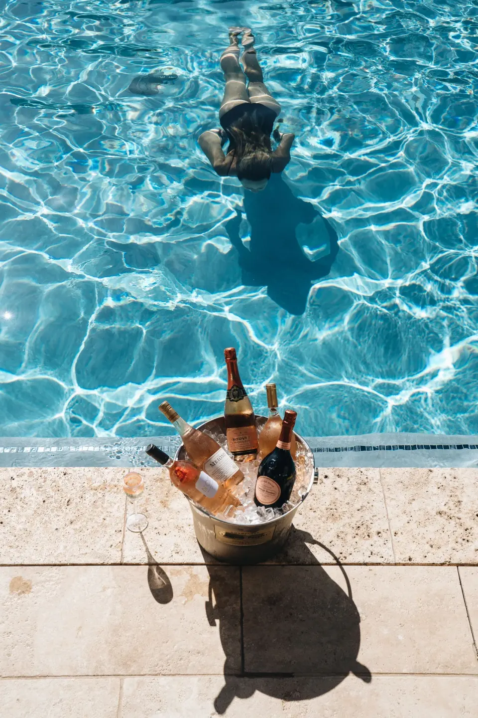 A swimmer glides through the pool near an ice bucket of sparkling wine at Hotel Wailea.