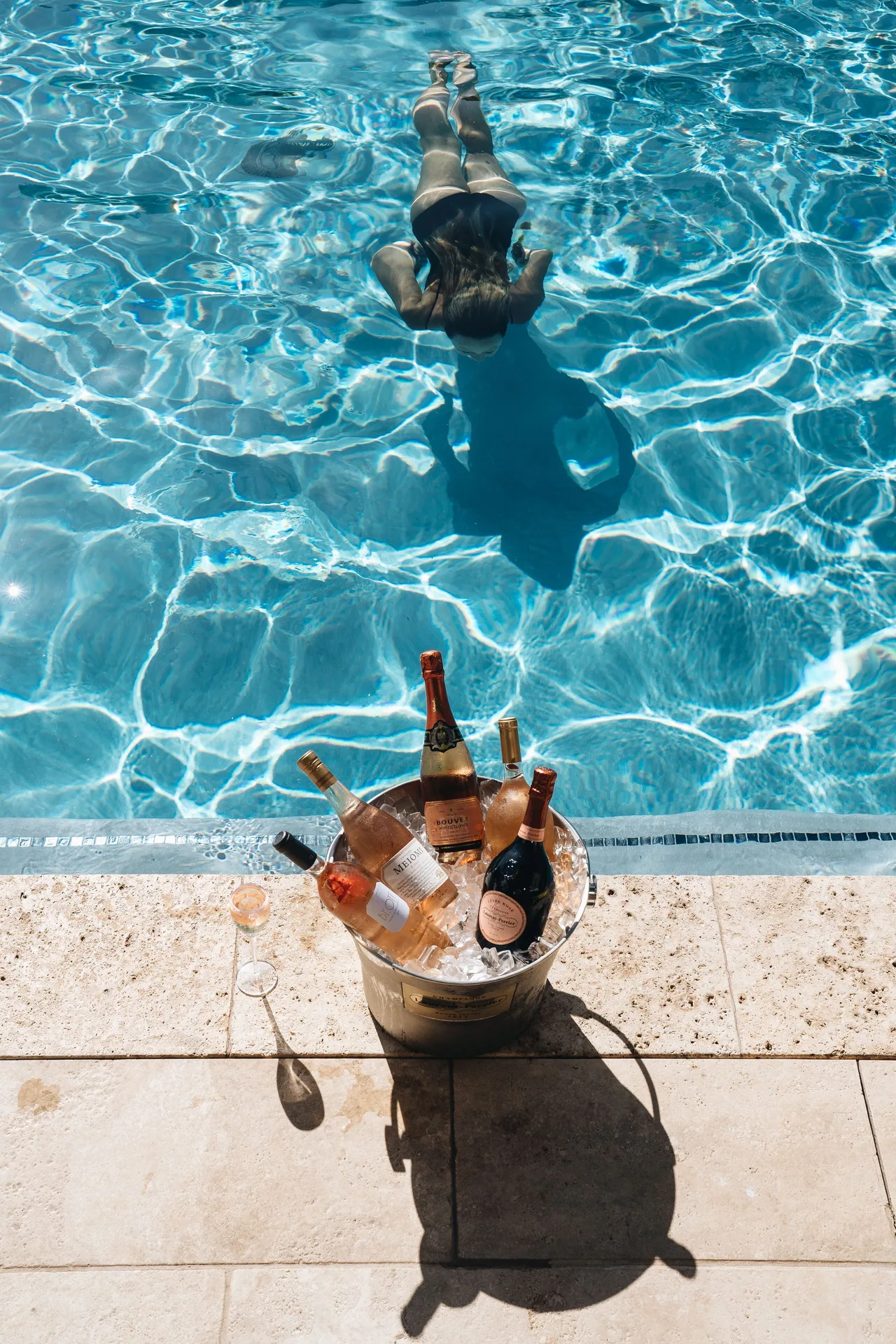 A swimmer glides through the pool near an ice bucket of sparkling wine at Hotel Wailea.