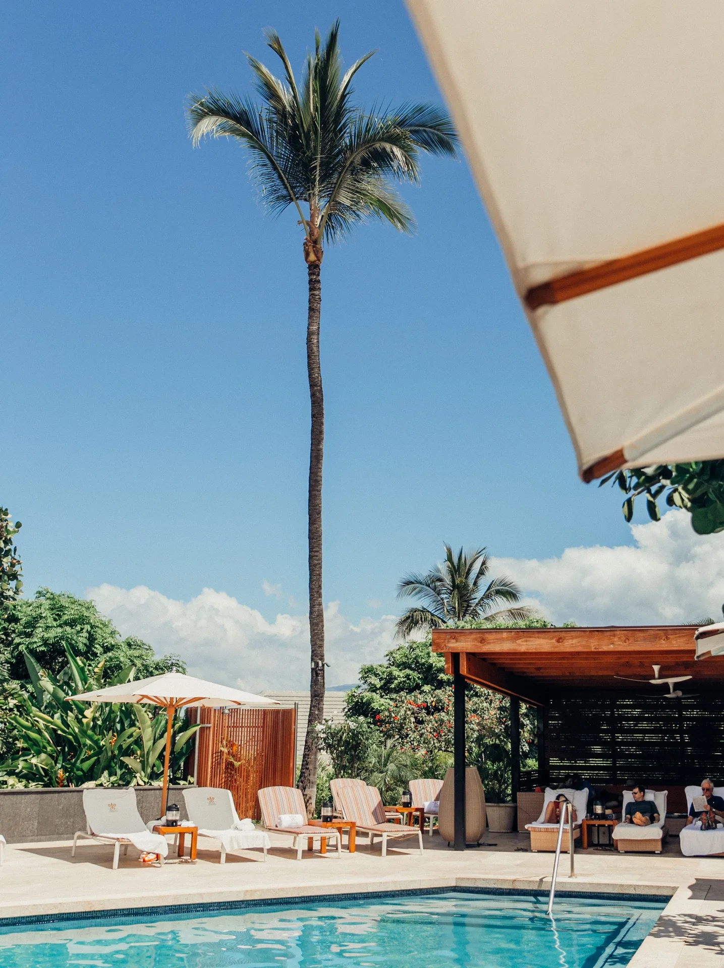 Palm trees, umbrellas, cabana seating, and pool steps at Hotel Wailea.