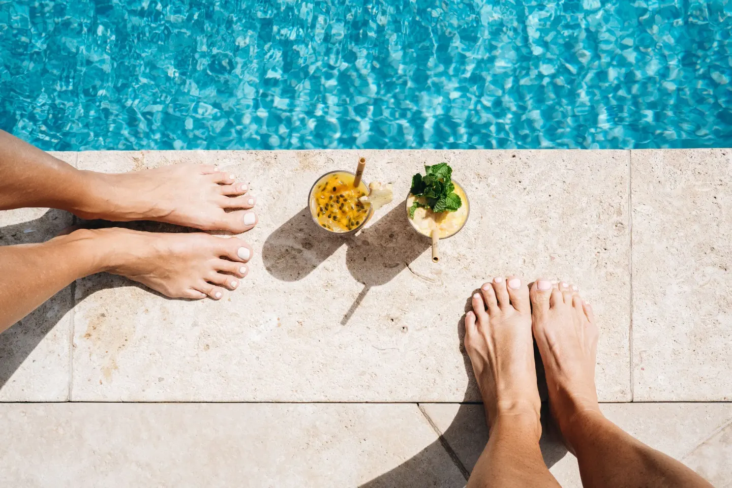 Poolside drinks on stone coping beside blue water and bare feet at Hotel Wailea.