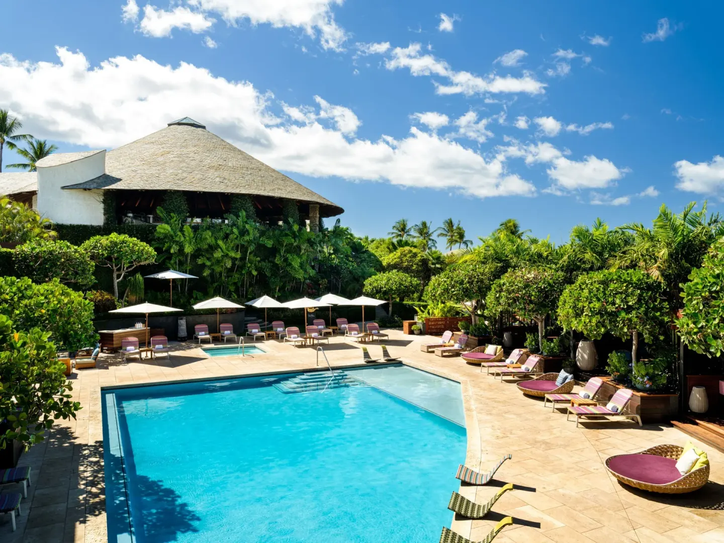 Pool deck with loungers, umbrellas, and tropical landscaping at Hotel Wailea.