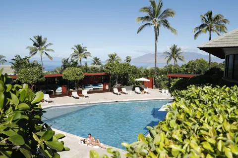 Resort pool with palm trees, loungers, ocean, and island view at Hotel Wailea.