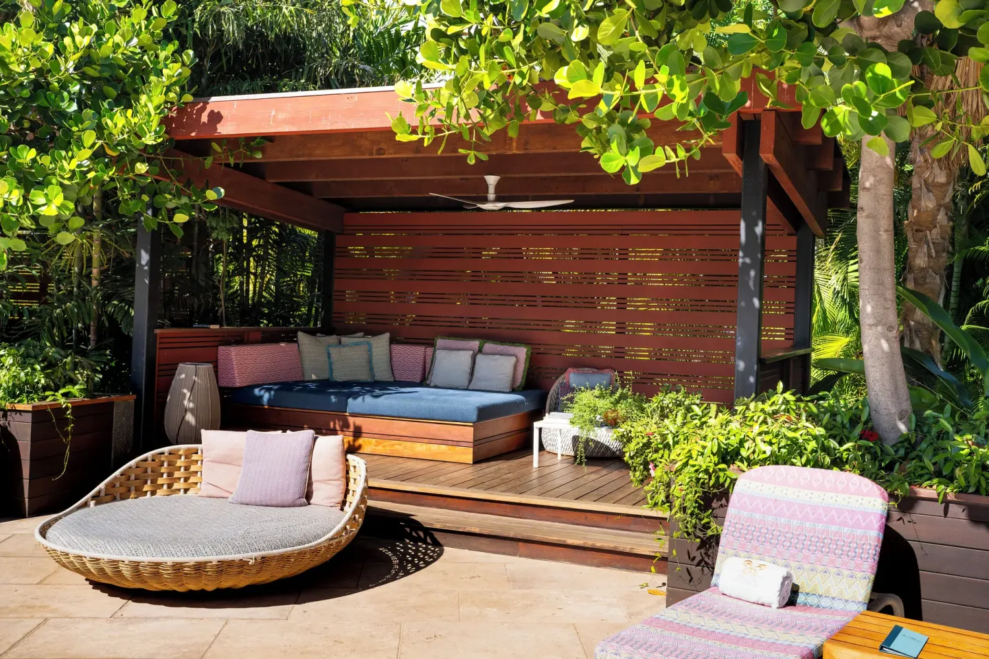 Shaded pool cabana with cushioned daybed, lounge chairs, and greenery at Hotel Wailea.