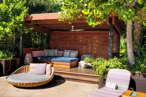 Shaded pool cabana with cushioned daybed, lounge chairs, and greenery at Hotel Wailea.