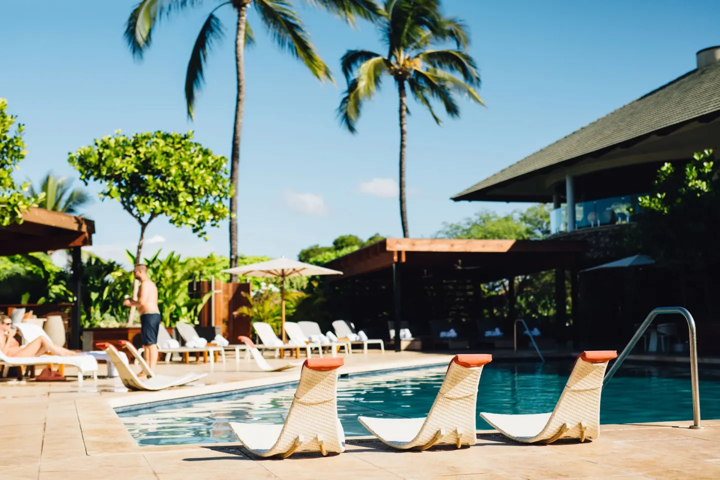 Lounge chairs, palms, and guests beside the pool at Hotel Wailea.