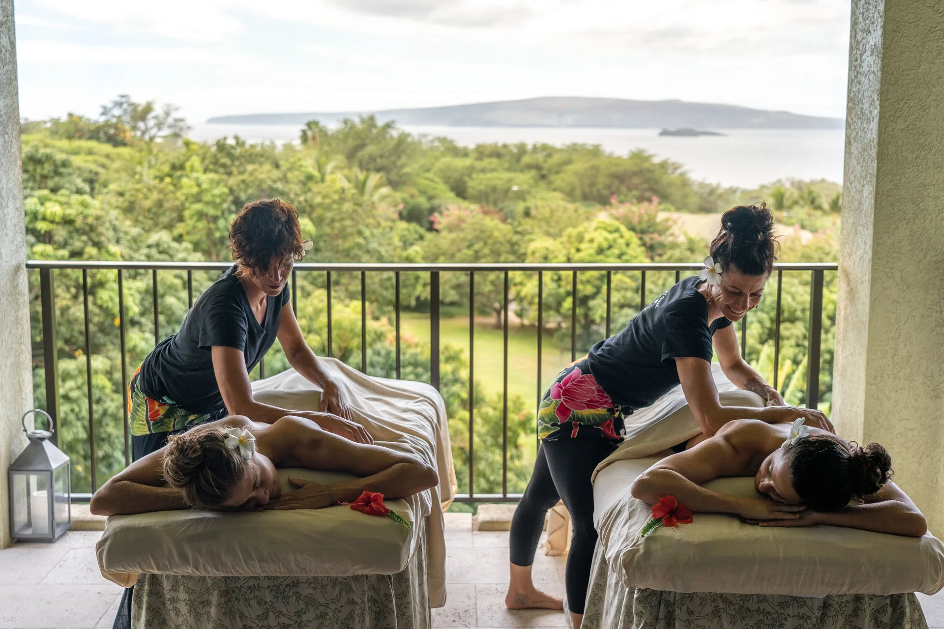 Two outdoor massage tables on a terrace overlooking greenery and ocean at Hotel Wailea.